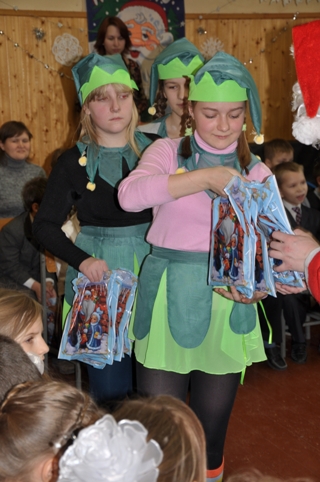 Эльфы помогают Санта Клаусу  раздавать подарки